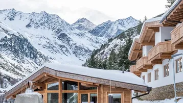 Traditionelles Holzhaus in den verschneiten Alpen mit beeindruckendem Bergblick und Holzbalkonen.