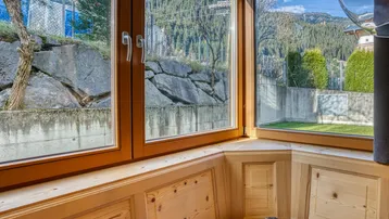 Gemütliche Sitzecke mit Holzvertäfelung und weitem Blick auf die Berge und grüne Landschaft.