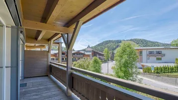 Geräumiger Holzbalkon mit traditionellem Geländer und einem weiten Blick auf die Berge.