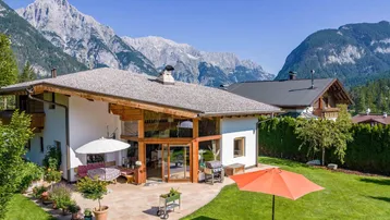 Großzügiger Gartenbereich mit Terrasse, Sonnenschirmen und beeindruckendem Bergblick.