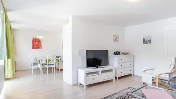 Helles Wohn- und Esszimmer mit Parkettboden, modernen Möbeln und Zugang zum Essbereich.