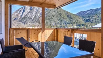 Überdachter Balkon mit Sitzgelegenheiten und atemberaubendem Panoramablick auf die Berge.