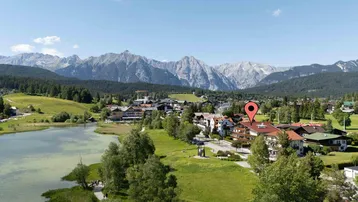 Luftaufnahme einer malerischen Stadt am Seeufer mit majestätischen Bergen im Hintergrund.