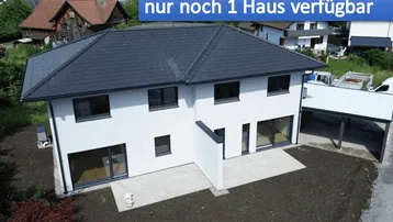 Modernes Einfamilienhaus mit weißer Fassade, dunklem Dach und großzügigen Fenstern, umgeben von Grünflächen.