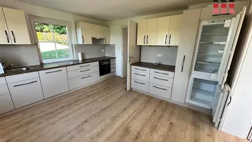 Helle Einbauküche mit modernen Schränken, Arbeitsplatten und integriertem Kühlschrank.