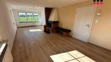 Geräumiges Wohnzimmer mit Kamin, Holzboden und großen Fenstern mit Weitblick.