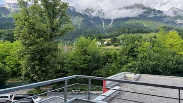 Weitläufiger Bergblick von einem Balkon, umgeben von grünen Bäumen und einer ruhigen Landschaft.