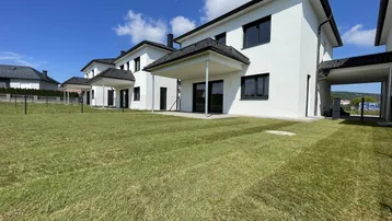 Moderne Reihenhäuser mit frisch angelegtem Rasen und sonnigem Gartenbereich.
