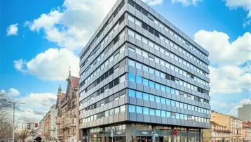 Modernes Bürogebäude mit Glasfassade und blauen Akzenten in städtischer Umgebung.