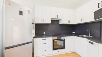 Moderne Küche mit weißen Schränken, dunkler Arbeitsplatte und integrierten Geräten, ideal für den täglichen Gebrauch.