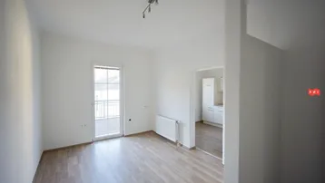 Helles Zimmer mit Holzboden, weiß gestrichenen Wänden und Zugang zu einem französischen Balkon.