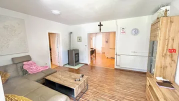 Gemütliches Wohnzimmer mit Laminatboden, Kaminofen und Blick in den angrenzenden Bereich.