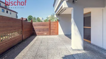Gepflasterter Außenbereich mit Holzzaun und direktem Zugang zum Gebäude.