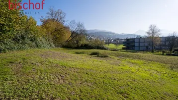 Weitläufiges Grundstück mit grüner Wiese und Blick auf die umliegende Landschaft und Berge.