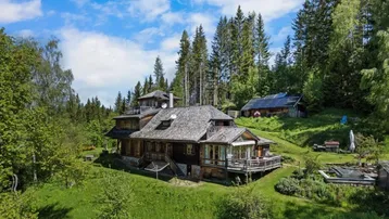 Charmantes Holzhaus in alpiner Umgebung mit grüner Landschaft und Photovoltaikanlage.