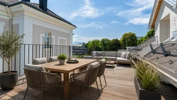 Große Dachterrasse mit Ess- und Lounge-Bereich, Holzboden und weitem Blick auf die Umgebung.