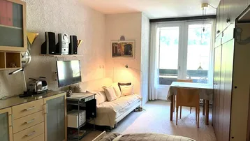 Gemütlicher Wohn- und Schlafbereich mit Esstisch und Zugang zu einem Balkon.