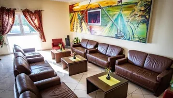 Geräumiger Loungebereich mit bequemen Ledersofas und einem großen, farbenfrohen Wandgemälde als Blickfang.