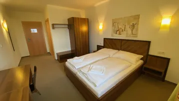Gemütliches Schlafzimmer mit Doppelbett, Holzmöbeln und indirekter Beleuchtung an den Wänden.
