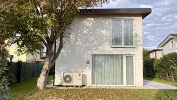 Modernes Einfamilienhaus mit weißer Fassade, großen Fenstern und einem gepflegten Garten.