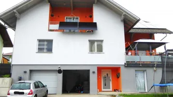 Modernes Einfamilienhaus mit Garage, Balkonen und Solaranlage an der Fassade.