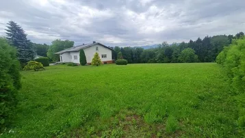 Einfamilienhaus mit großem Rasen und Blick auf die umliegende Natur und Berge.