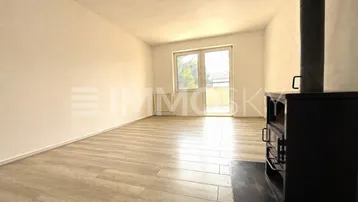 Helles Wohnzimmer mit modernem Laminatboden, einem Holzofen und Zugang zu einem Balkon oder Garten.