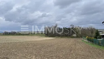 Weitläufiges Feldgrundstück unter bewölktem Himmel mit Blick auf die weite Landschaft.