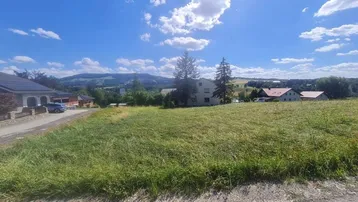Weitläufiges Grundstück mit grüner Wiese und Blick auf die umliegende Hügellandschaft unter blauem Himmel.