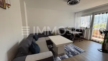 Helles Wohn- und Esszimmer mit modernem Sofa, Esstisch und Zugang zum Balkon.
