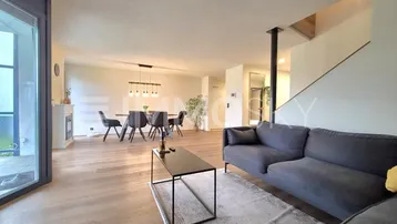 Heller offener Wohn- und Essbereich mit modernem Sofa, Holzboden und Zugang zum Außenbereich.