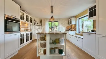 Helle Küche mit weißen Schränken, Kücheninsel und Holzboden, modern eingerichtet.