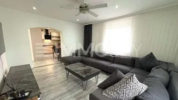 Helles Wohnzimmer mit großem Ecksofa, Deckenventilator und Blick in die offene Küche.