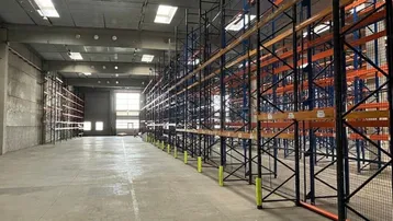 Geräumige Lagerhalle mit hohen Regalen und Betonboden, bereit für die Nutzung.