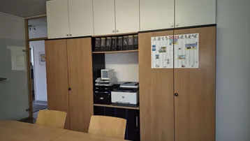 Funktionaler Büroraum mit integrierten Schränken und einem großen Besprechungstisch für effizientes Arbeiten.