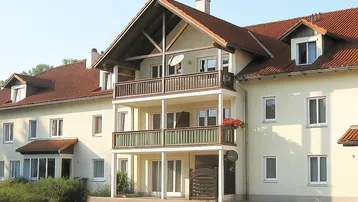 Ansicht eines Mehrfamilienhauses mit mehreren Balkonen und einem markanten Satteldach.