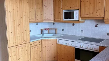 Rustikale Küche mit Holzschränken, integrierten Geräten und Holzbalkendecke.