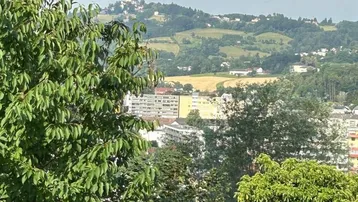 Panoramablick über grüne Hügel und eine Stadt mit einer Kirche in der Ferne.