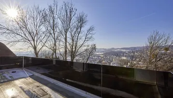 Weitblick über die Stadt und die verschneite Landschaft von einer Dachterrasse.
