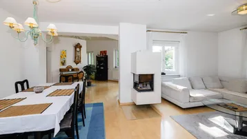 Offener Wohn- und Essbereich mit Kamin, hellem Parkettboden und modernem Mobiliar.