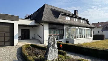 Großzügiges Einfamilienhaus mit Mansarddach, Wintergarten und integrierter Doppelgarage.