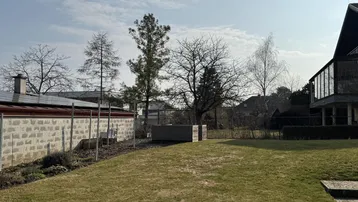 Sonnige Gartenfläche mit Rasen, Bäumen und Blick auf die Umgebung, inklusive Photovoltaikanlage.
