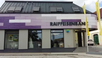 Modernes Geschäftsgebäude mit farbiger Fassade und Dachfenstern, beherbergt eine Bankfiliale.
