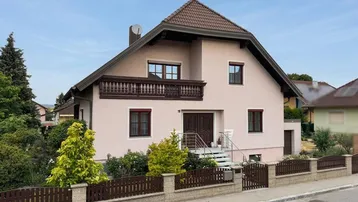 Einfamilienhaus mit Satteldach, Balkon und gepflegtem Vorgarten.