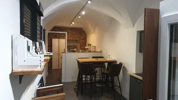 Geräumiger Geschäftsraum mit markanter Gewölbedecke, Thekenbereich und Ausstellungsstücken für Fenster. Die Holzvertäfelung verleiht dem Raum eine warme Atmosphäre.