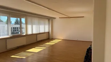 Geräumiger und heller Gewerberaum mit großen Fenstern, Holzfußboden und viel Tageslicht.