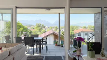 Helles Wohnzimmer mit Zugang zur Terrasse und weitem Bergblick durch große Fenster.