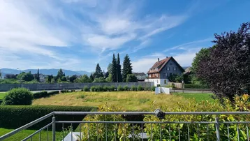 Großer Balkon mit Panoramablick auf die umliegende Natur und die Berge im Hintergrund.