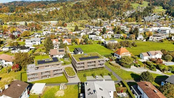 Weitläufige Luftaufnahme von zwei modernen Wohngebäuden mit Gründächern und Bergblick.