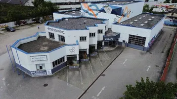 Luftaufnahme eines modernen Geschäftsgebäudes mit blauen Akzenten und einem großen Parkplatzbereich.